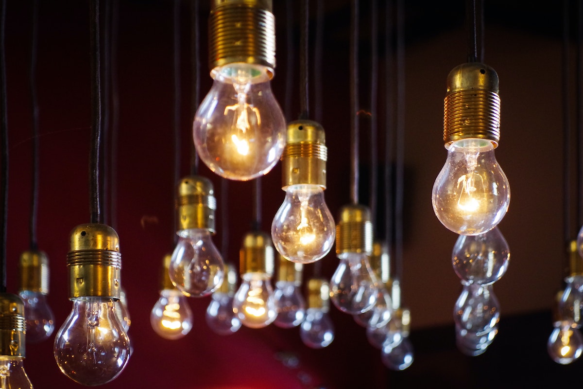 A series of light bulbs - some lit - hanging from a ceiling